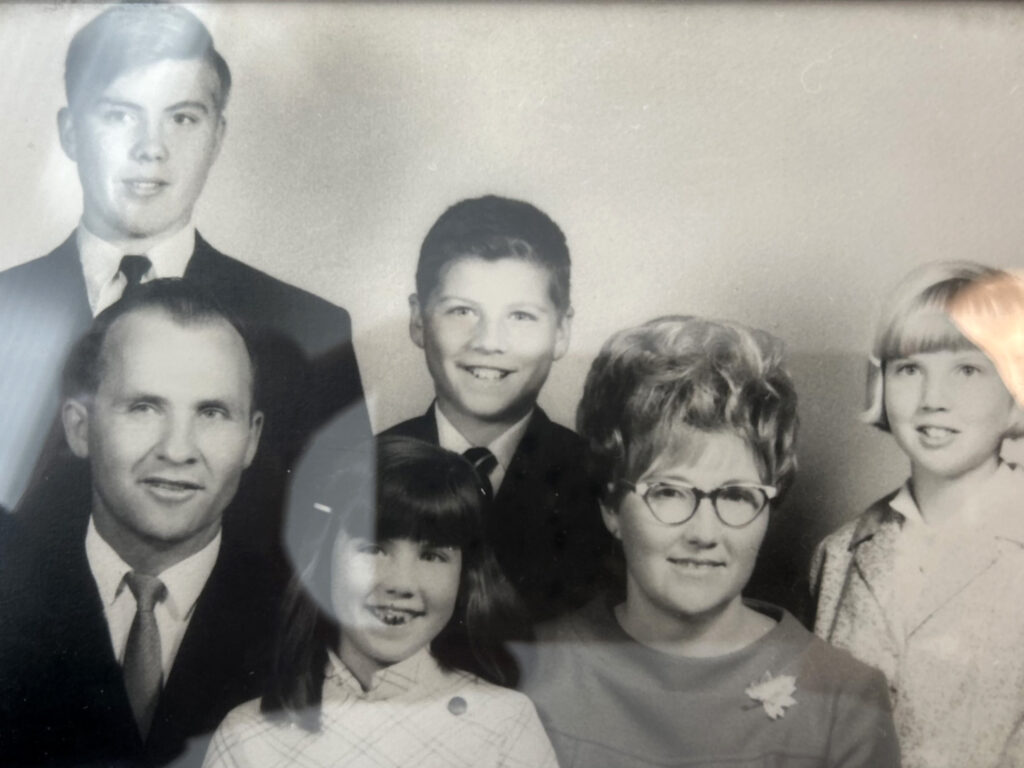 An old family photo: a man, a woman, and two children posing together. Evelyn is also present in the picture.
