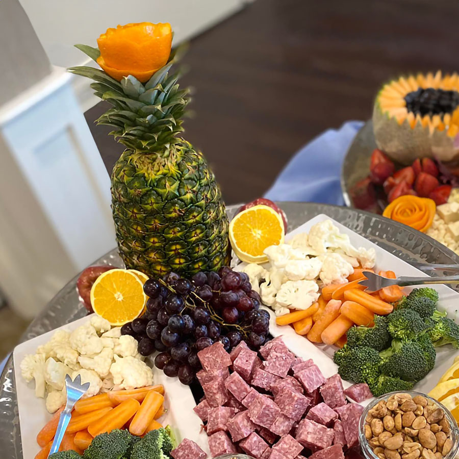 A pineapple surrounded by a variety of fruits, veggies, and meats on a platter. Perfect for a Happy Hour Event!