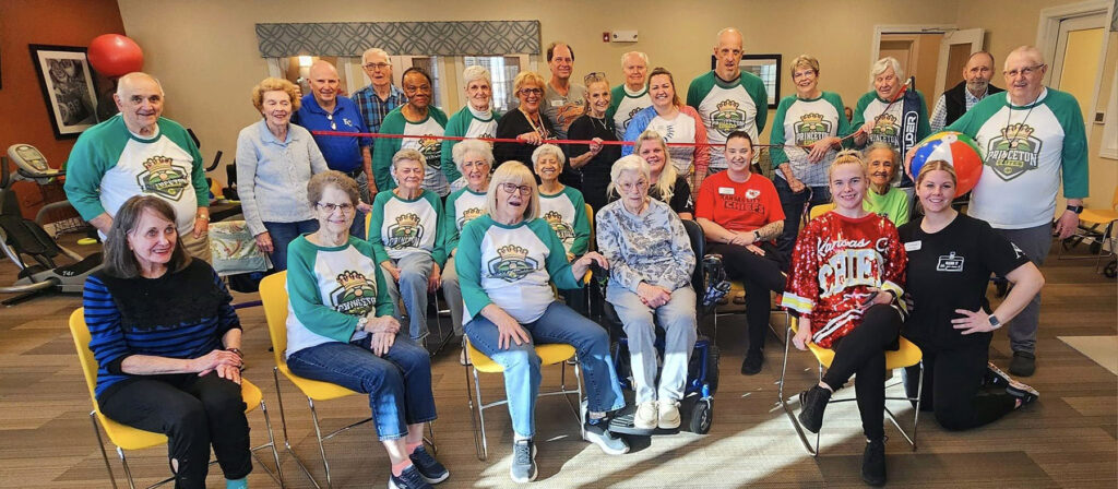 Princeton Senior Living chairs beach volleyball team residents and employees in green baseball tees with the team Elites' name.