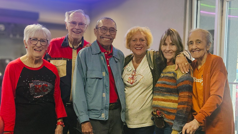 A group of senior friends smile together, enjoying a night out.