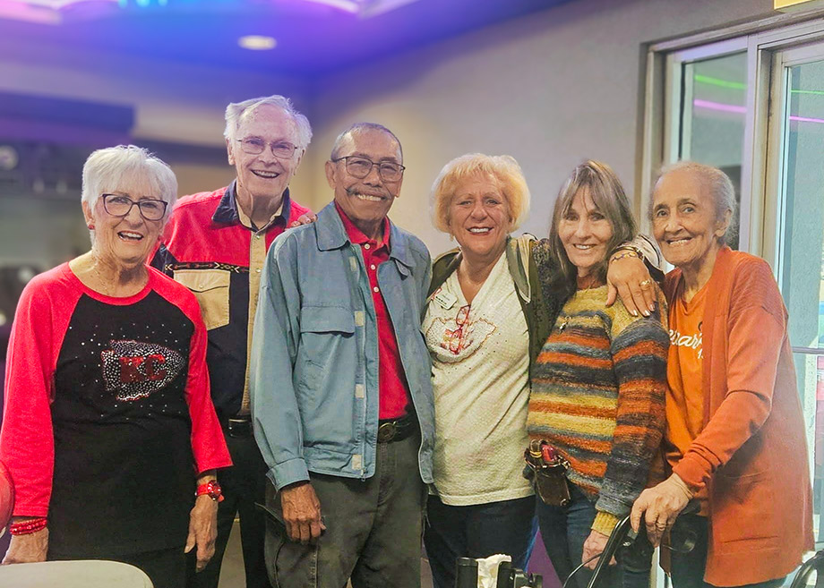 A group of senior friends enjoy the local nightlife with big smiles.