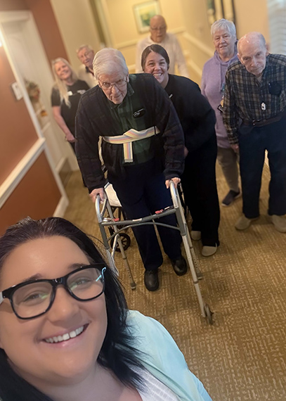 A team member takes a selfie with a group of smiling senior residents.
