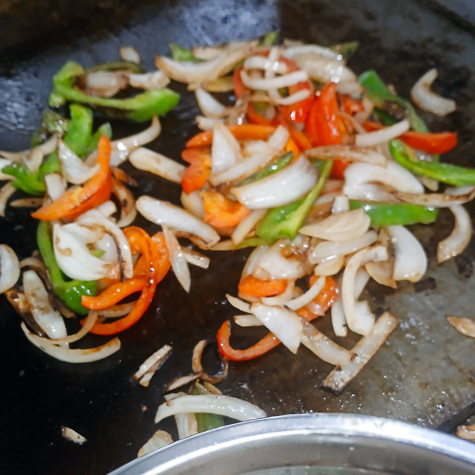 Fresh onions and bell peppers sizzling at The Princeton Senior Living, ready to be used in chef-prepared dishes.